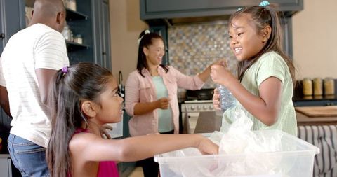 Family Recycling Together in Kitchen Helping Environment