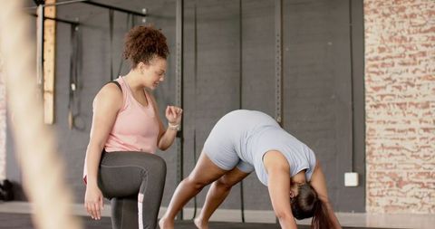 African american trainer guiding client through dynamic stretch in urban gym