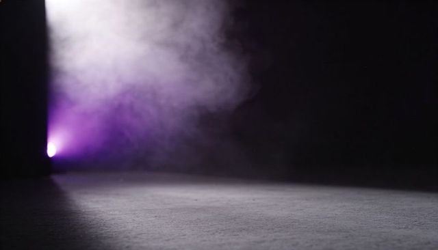 Casting purple spotlight and rising fog across empty stage floor creating cinematic mood