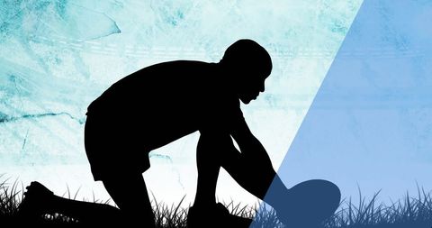 Rugby player silhouette positioning ball on grass