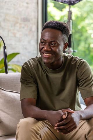 Smiling african american presenter recording in home studio on sofa with natural light