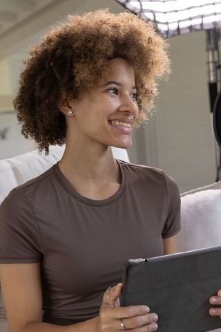 African american content creator streaming from home studio holding tablet and smiling