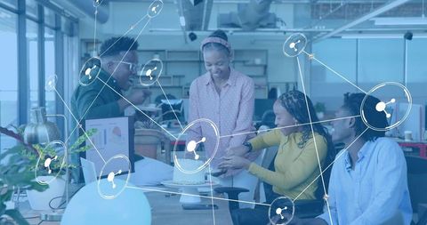 Office team celebrating milestone with cake, collaborating around desk with network overlay