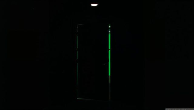 Partly opening door releasing emerald glow in dark minimalist interior