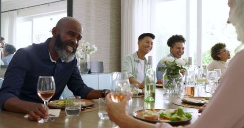 Friends sharing laughter and wine at joyful wedding celebration dinner