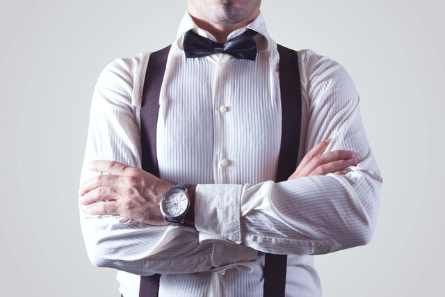 Man wearing white dress shirt, black suspenders, and bow tie, with arms crossed, radiating confidence. The image is useful for themes related to business, fashion, confidence, professionalism, and style, ideal for websites, blogs, presentations, or marketing materials.