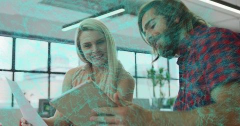 Two colleagues reviewing tablet and documents in bright modern office collaborating