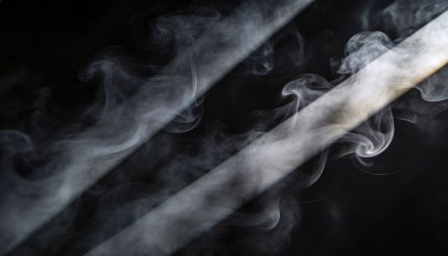 Curling diagonal smoke ribbons over deep black backdrop abstract monochrome haze soft lit