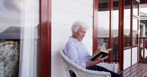 Senior Woman Enjoying Reading Book on Balcony