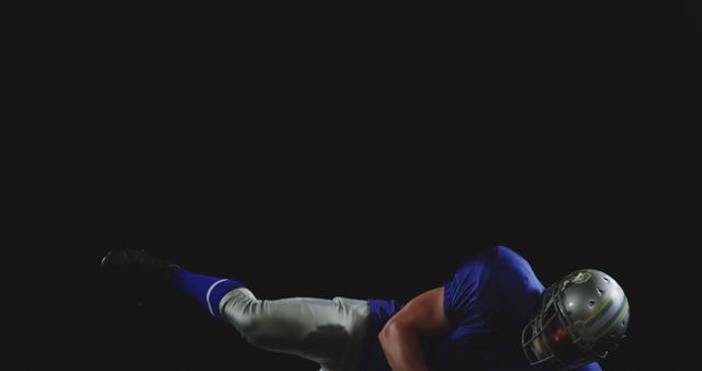 American football player in full uniform dives through air against black background. Suitable for sports training videos, advertisements for sports equipment, motivational content, football team promotions.