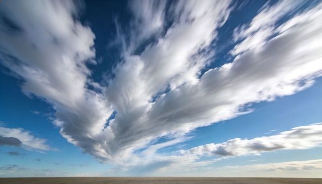 Expansive streaking cloud formation rising above barren salt flat horizon, dramatic blue sky