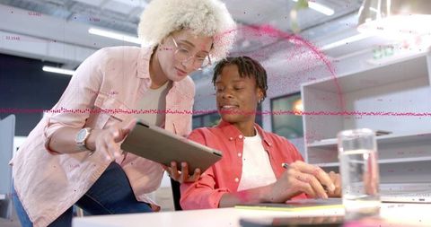 Young professionals collaborating on tablet with analytics overlay in modern open office