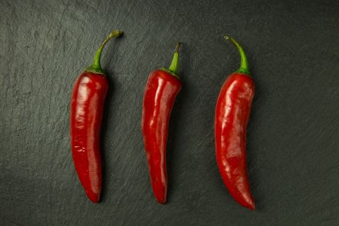 Three red chili peppers on dark slate background