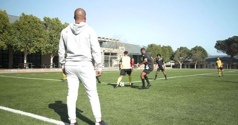 Coach observing soccer practice on sunny day