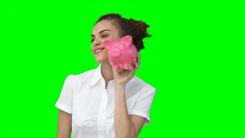 Woman Smiling Holding Piggybank Against Green Background