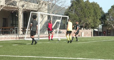 Soccer game on bright day with players near goal