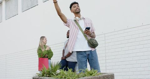 Young Diverse Friends Laughing on Urban Sidewalk Holding Smartphone and Shopping Bag