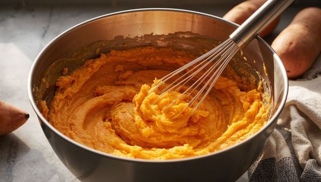 Whisking Mashed Sweet Potatoes in Steel Bowl on Sunlit Rustic Kitchen Counter