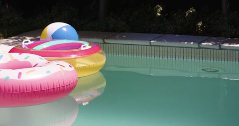 Colorful pool floats and beach ball in refreshing pool