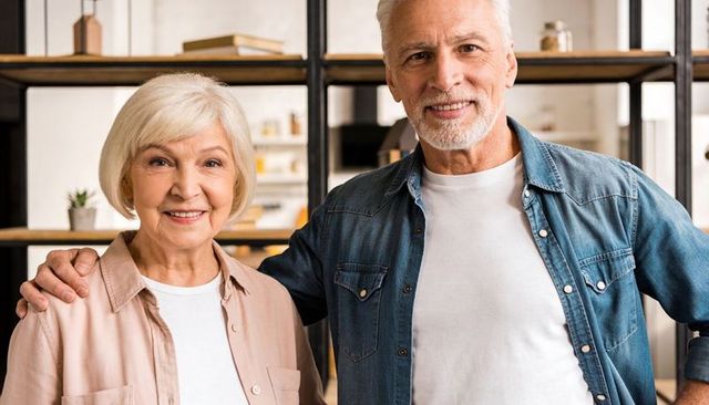 Smiling senior couple enjoying cozy life and companionship in kitchen with wooden shelving