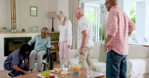 Caregiver assisting elderly friends in relaxed living room gathering