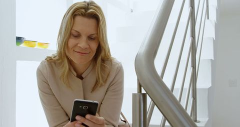 Smiling Woman Texting on Smartphone in Bright Modern Home