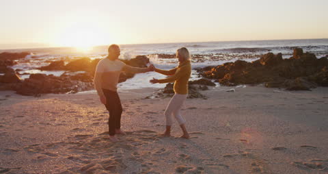 Senior Couple Dancing on Beach at Sunset in Joyful Embrace