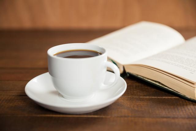 Close-up of coffee cup and book on wooden table