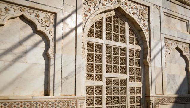Marble jali window with floral inlay and geometric lattice casting diagonal shadows on monument wall