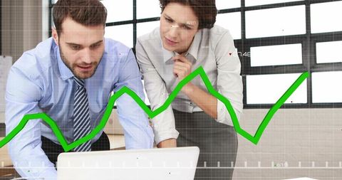 Business colleagues analyzing upward green sales chart on laptop in collaborative office data review