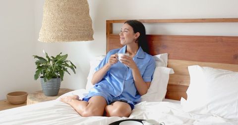 Joyful Woman Enjoying Morning Coffee in Cozy Bedroom