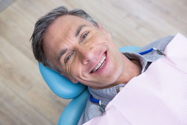 Overhead portrait of smiling man sitting on chair at dentist clinic
