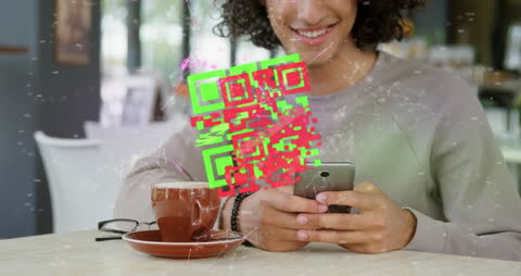 Smiling Woman Scans QR Code with Smartphone in Cafe