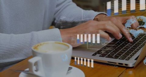 Typing hands on laptop with coffee and digital analytics overlay in cozy cafe workspace