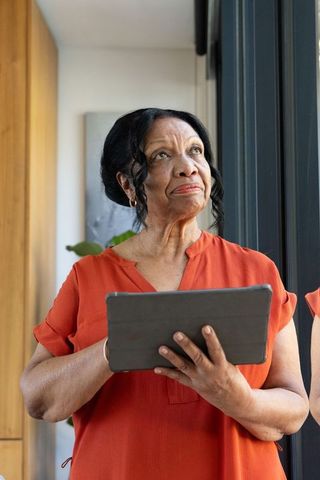 Senior african woman using tablet by window in sunlit modern minimalist home