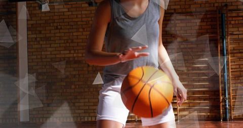 Teenage female dribbling basketball in school gymnasium during training, dynamic action