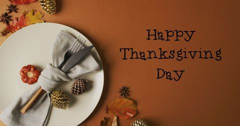 Thanksgiving celebration table setting with cutlery and pine cones