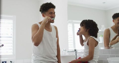 Father and son bonding while brushing teeth in bathroom