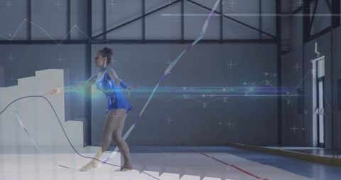 Graceful rhythmic gymnast performing ribbon routine in blue sequin leotard on indoor mat