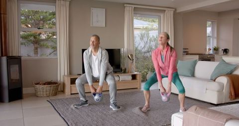 Senior couple exercising with kettlebells at home
