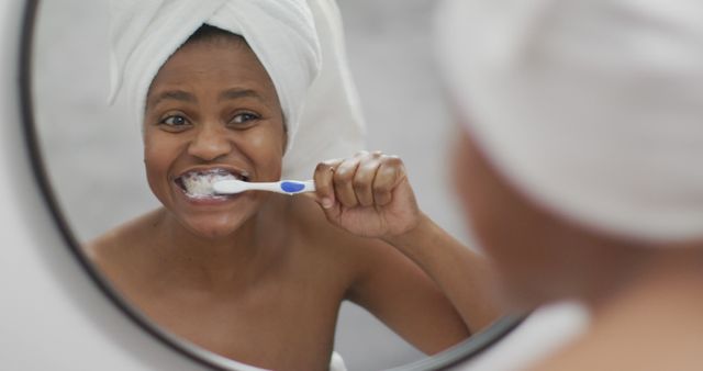 Happy african american woman brushing teeth in bathroom. domestic lifestyle, spending free time at home.