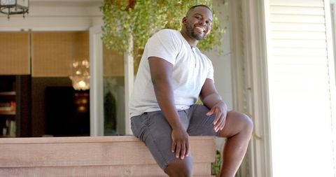 Smiling African American Man Relaxing in Sunlit Backyard Garden