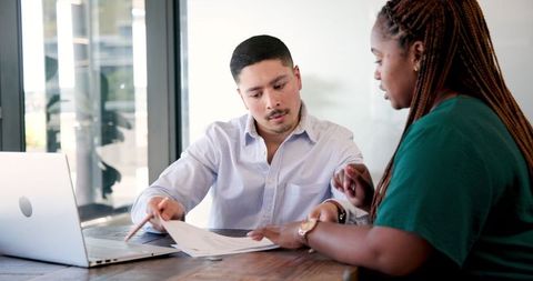 Colleagues Discussing Important Business Documents at Office Desk