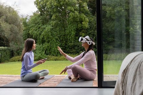 Asian women practicing yoga outdoors while exploring virtual reality headset