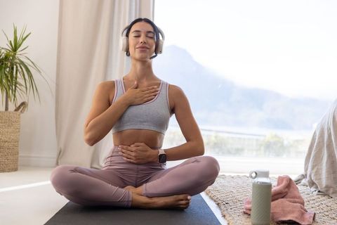 Calm at-home guided meditation: woman practicing mindful breathing with headset and yoga mat