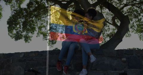 Women leaning on wall beneath tree with bicycle in park