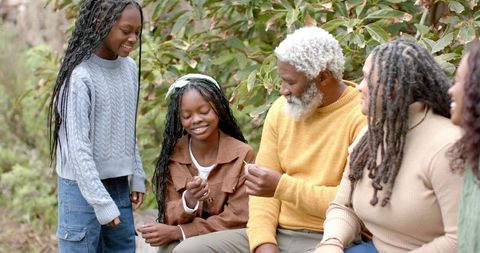 Multigenerational family exploring nature together, grandfather teaching kids about seeds