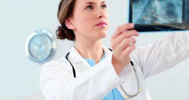 Female doctor analyzing x-ray image in a medical office. Perfect for healthcare, medical services, hospital promotions, patient diagnostics, medical research, and doctor office imagery.