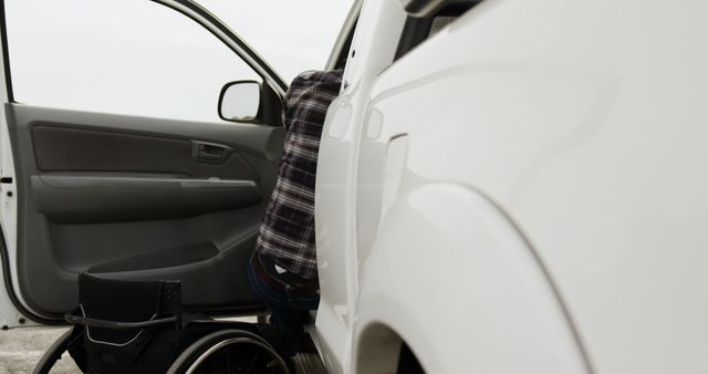 This image shows a person transferring from a wheelchair to a car, indicating the theme of independence and accessibility in everyday life. It can be used for blogs, articles, or informational content on disability services, mobility aids, accessibility in transportation, and personal autonomy.