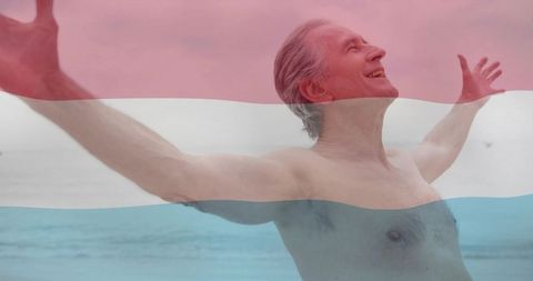 Joyful man embracing ocean breeze with flag overlay
